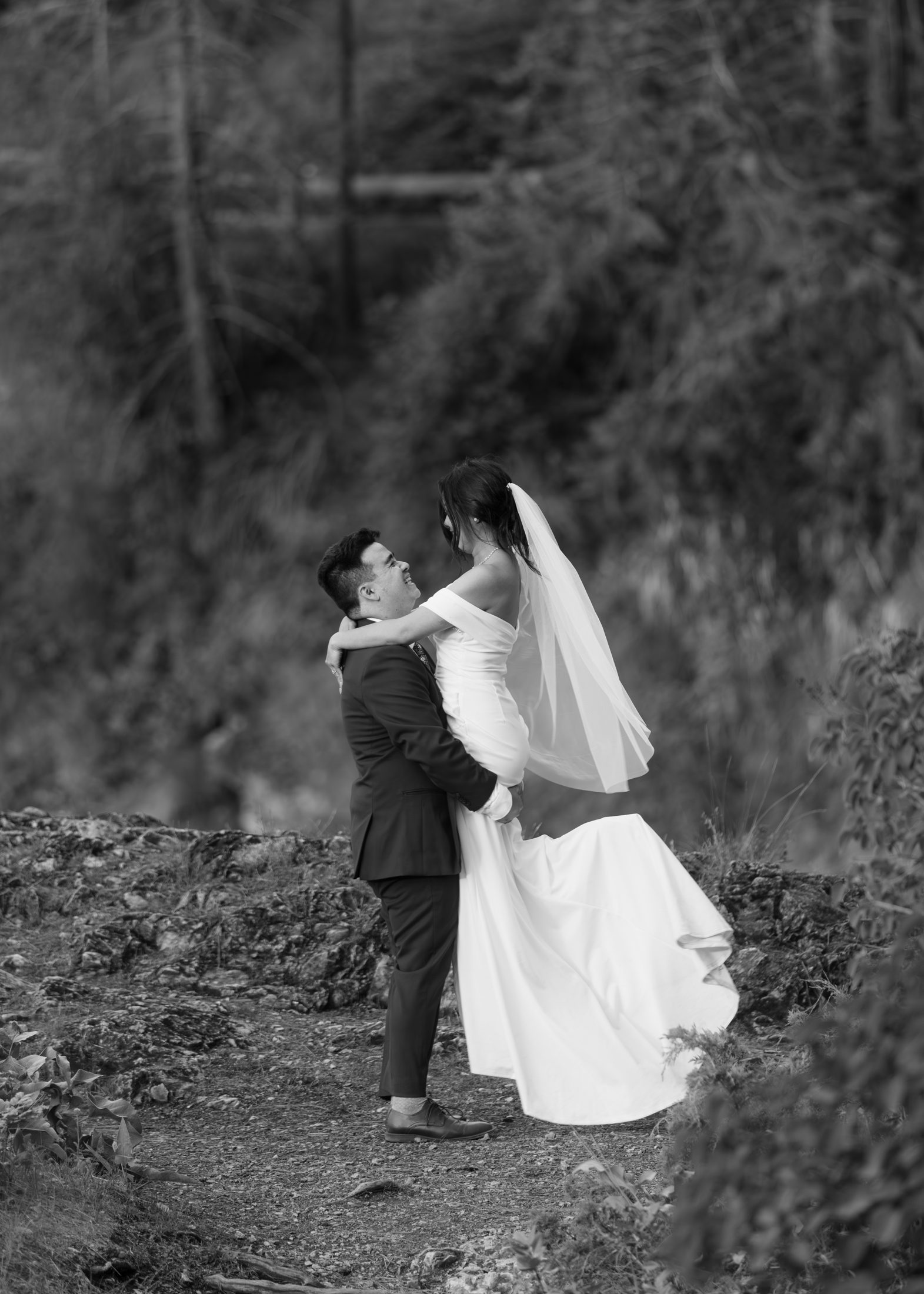 A groom lifting his bride on a forest trail